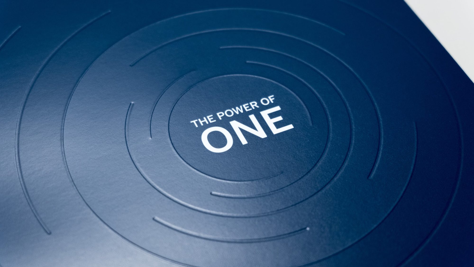 Cover showing report title "The Power of One" with surrounding emboss/deboss ripple effect